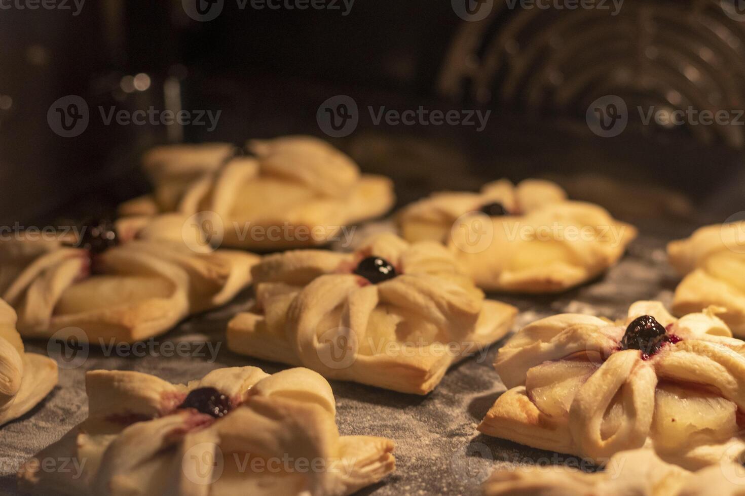 Puff pastry with pineapple wedges wrapped and cherry on top, on the baking tray baking in the oven. Food, hobby photo