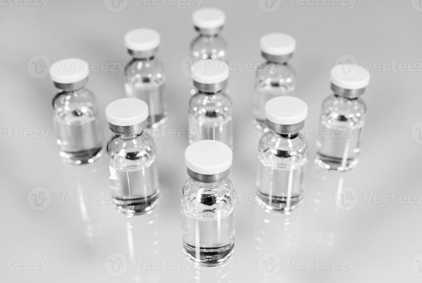 Medical vials with transparent liquid medication on light background photo