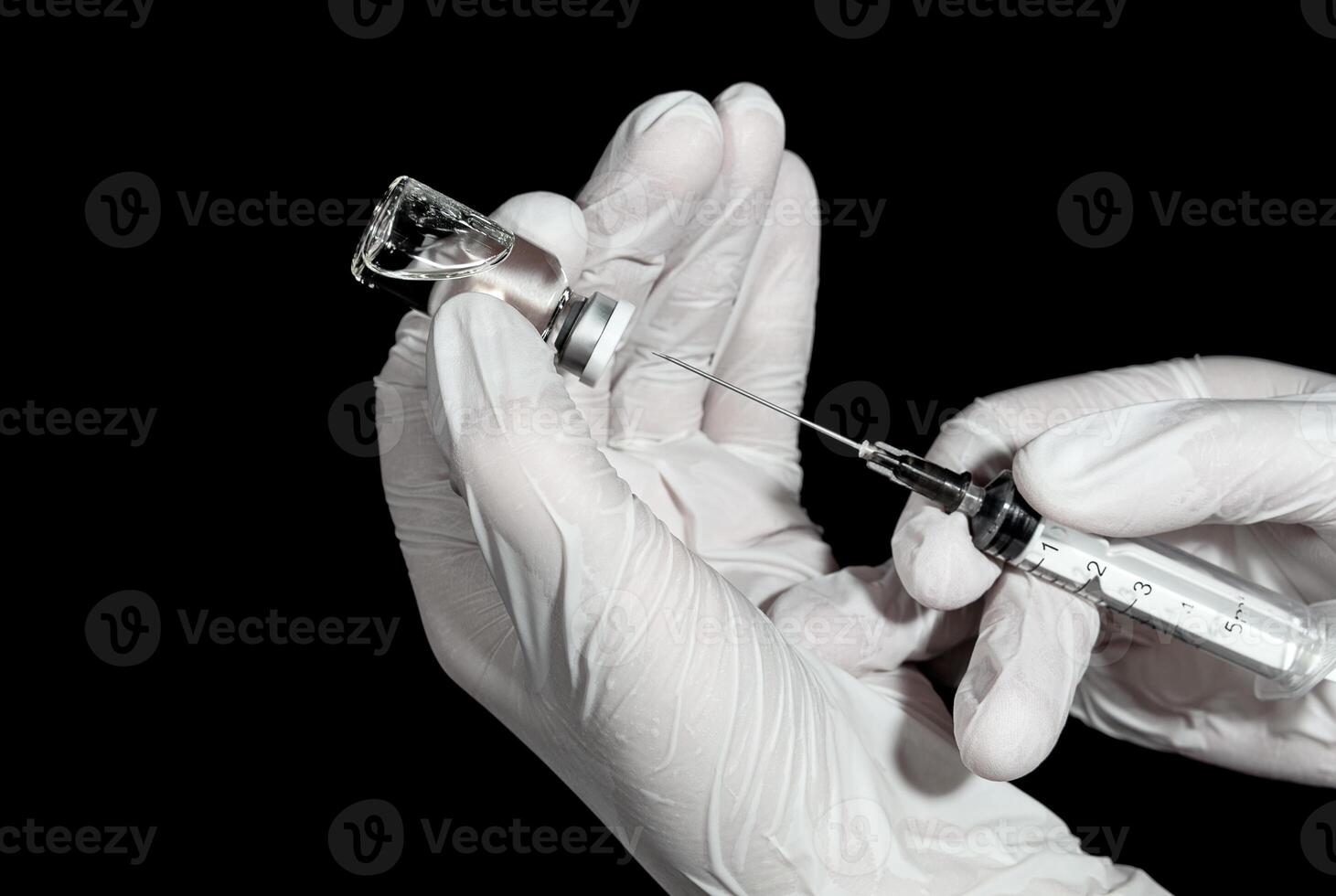 Medic's hands in a gloves with a syringe and a vial of vaccine photo