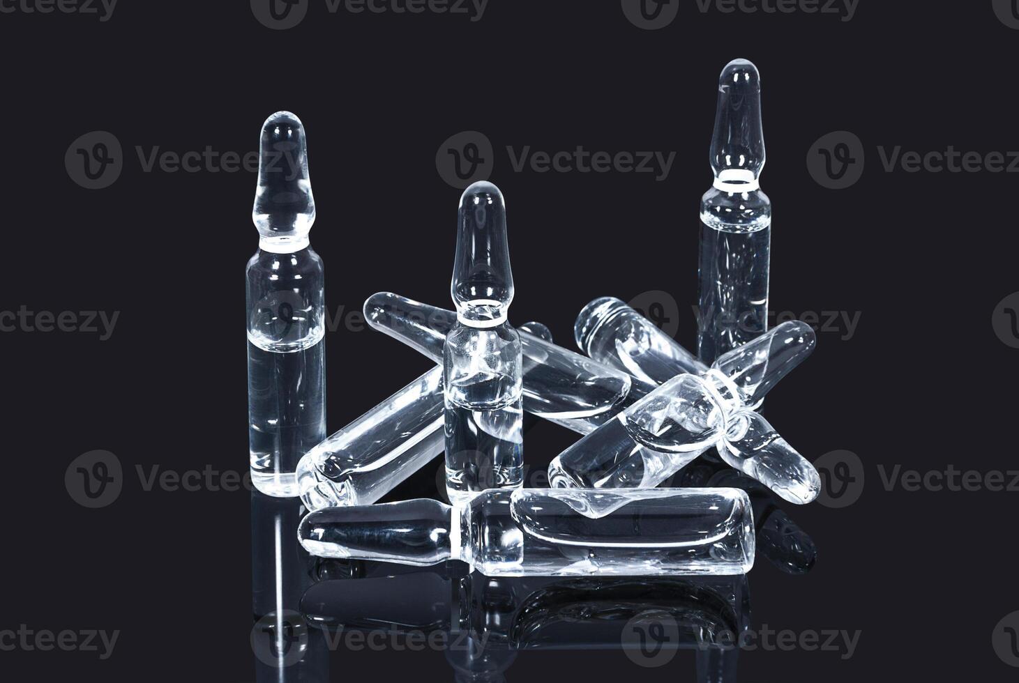 Heap of medical ampules with transparent vacccine on dark baclground photo