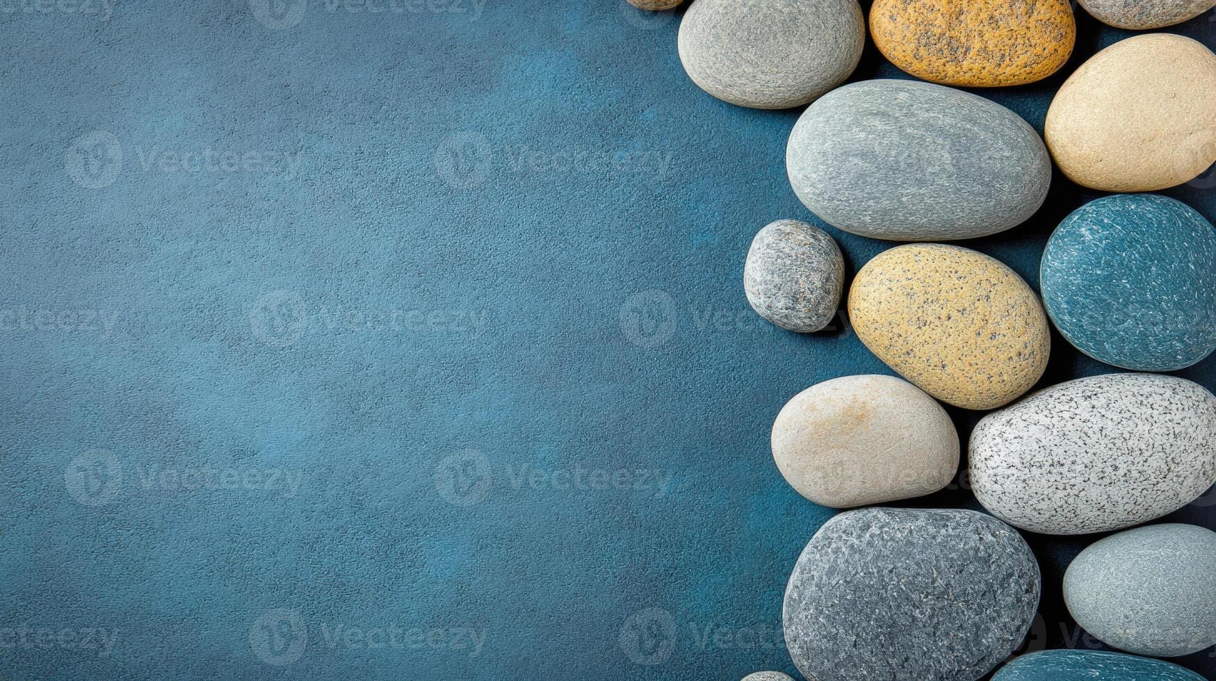 Smooth Sea Stones Bordering Deep Blue Surface Creates Calming Coastal Motif photo
