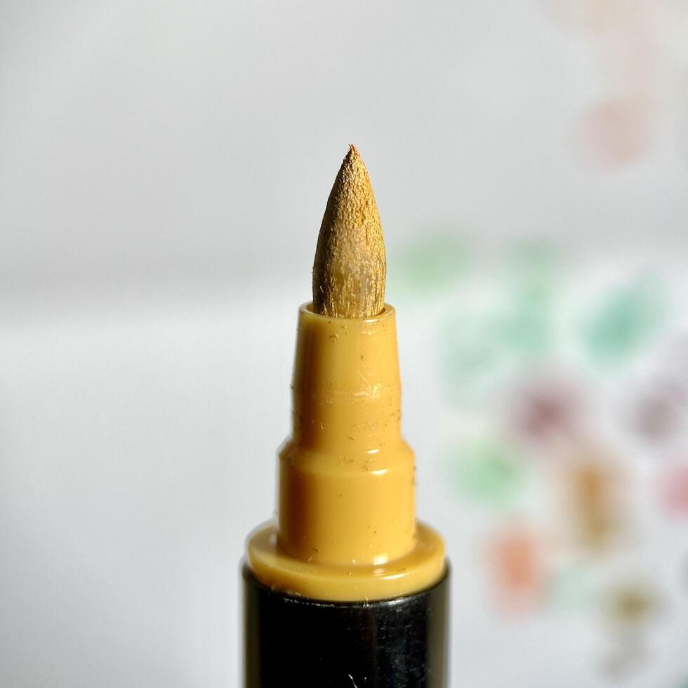 Close up brown stationary brush marker tip isolated on square paper surface background. photo