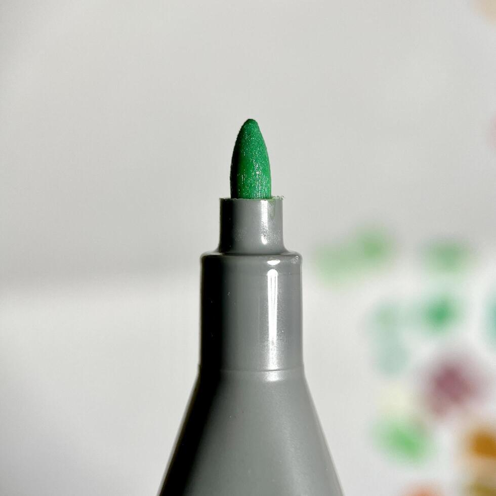 Close up green marker stationary felt nib isolated on square paper surface background. photo