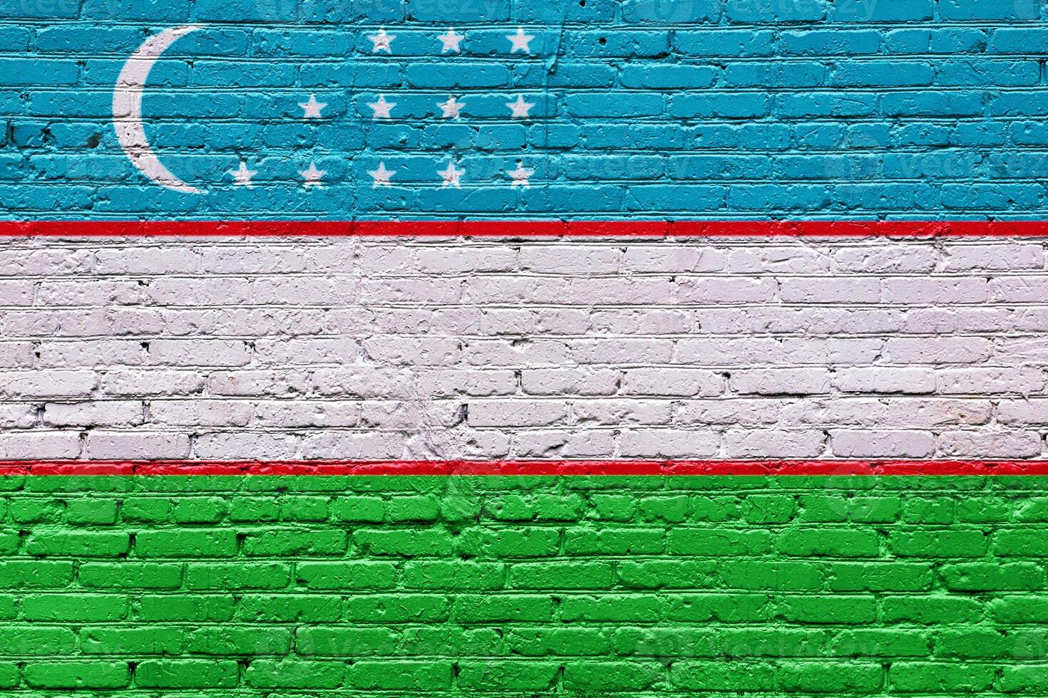 Abstract graffiti of uzbekistan flags on a textured brick wall with a grunge and rough surface photo