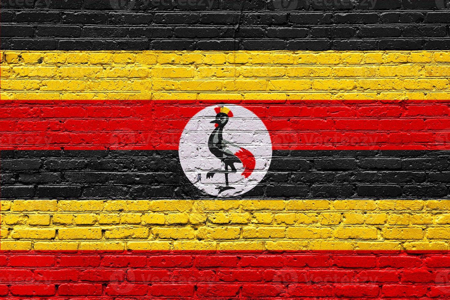 A weathered brick wall displays the grunge texture of the uganda flag, a national symbol, alongside the aged pattern of the Belgian flag photo