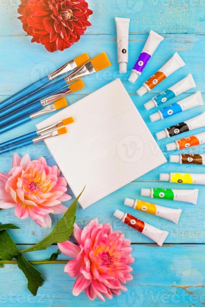 summer background. paints, brushes and a canvas on a blue wooden background. art. space for a text photo