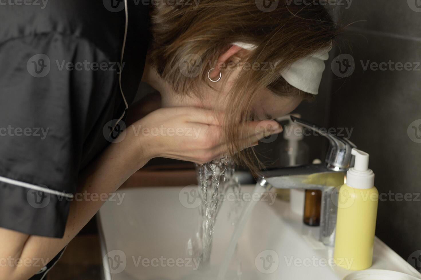 A woman washes her face in the bathroom photo