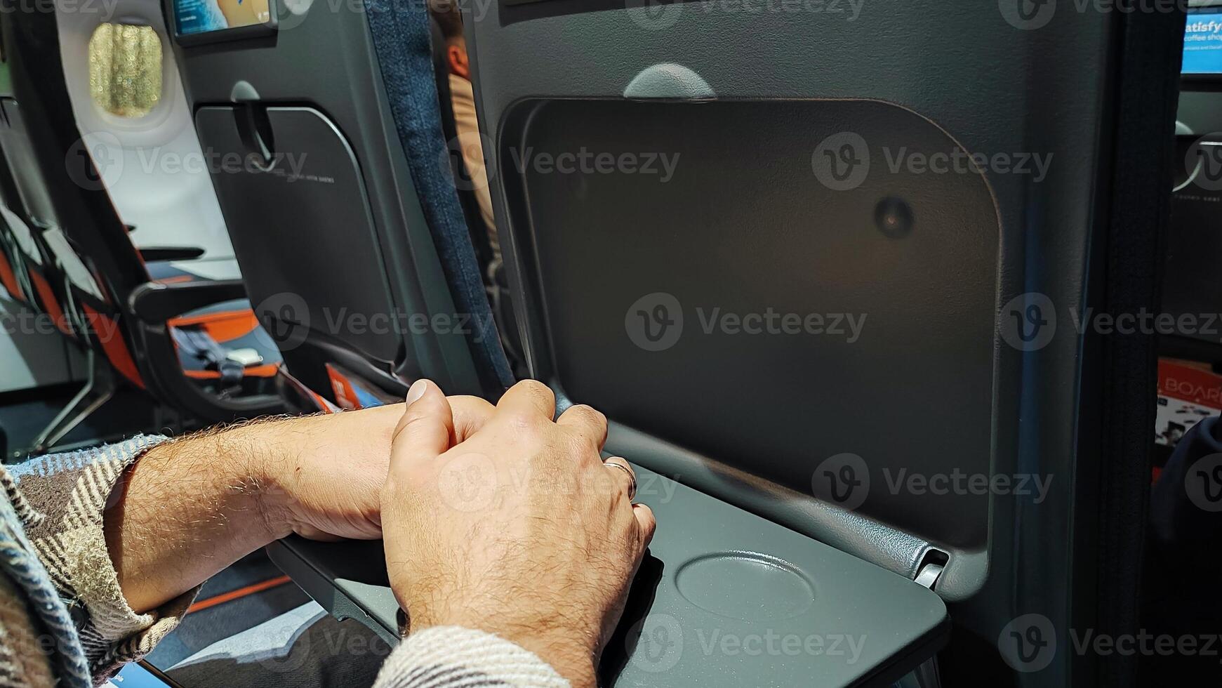 Empty airplane cabin. Male hands on a the table in the airplane cabin during landing photo