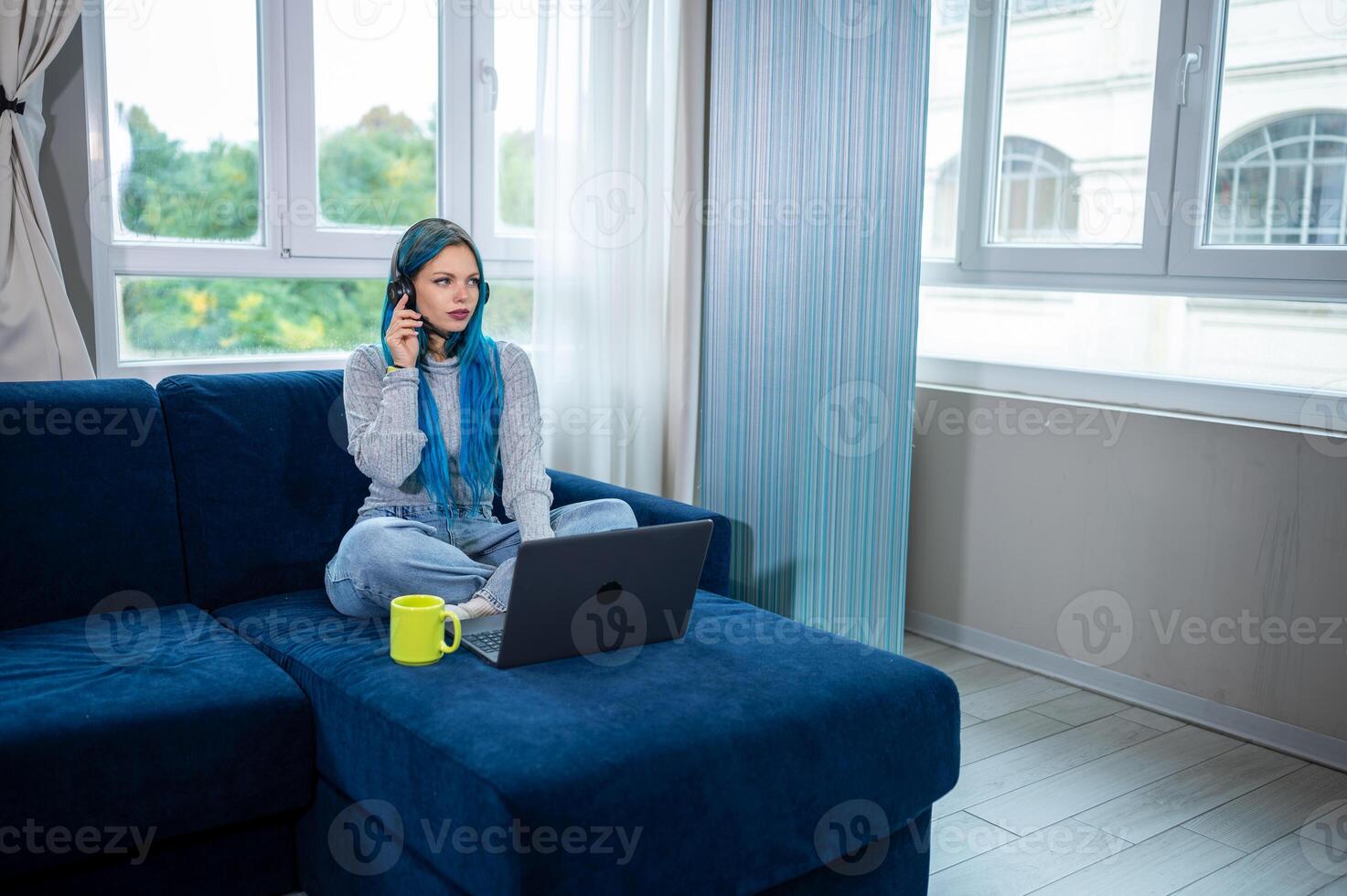 A woman sitting on a couch with a laptop and talking on the phone photo