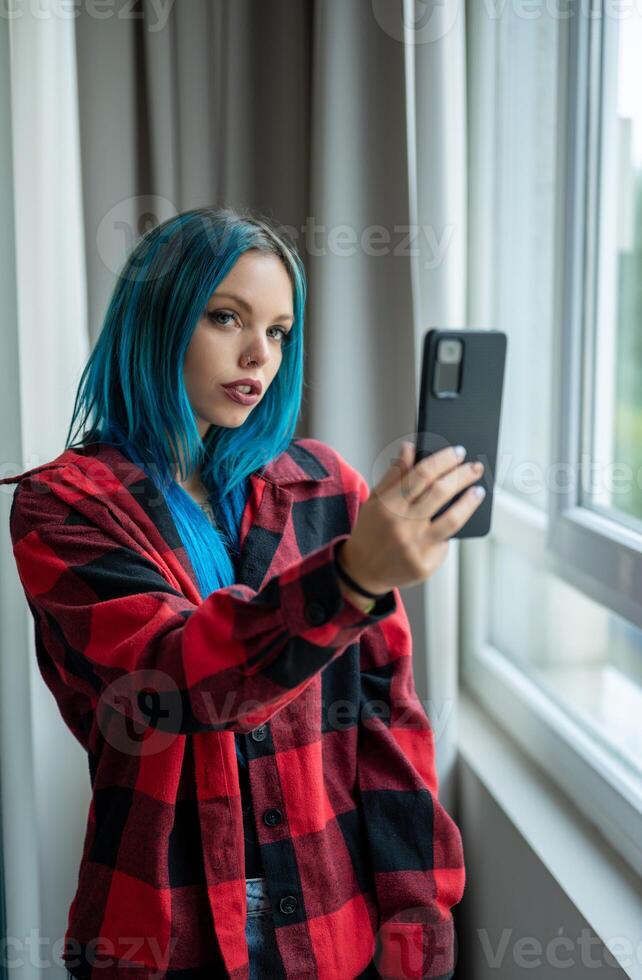 A woman with blue hair taking a selfie photo