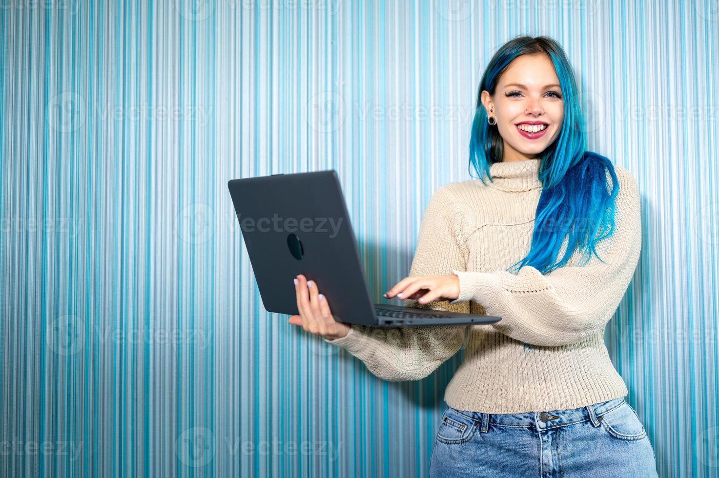 A woman with blue hair holding a laptop. photo