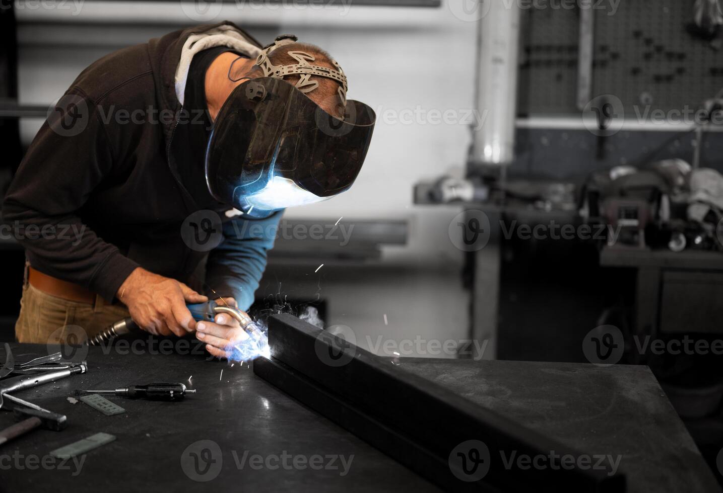 A man in a welding helmet working on a piece of metal photo