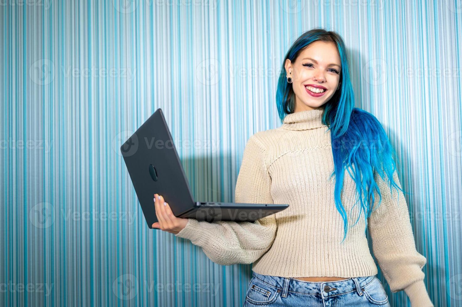 A woman with blue hair holding a laptop, photo