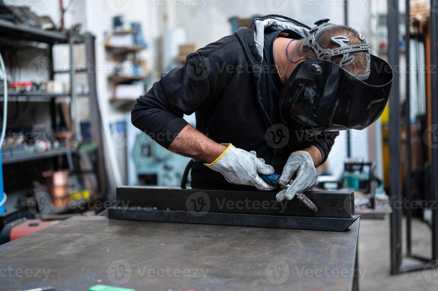 A man in a welding helmet working on a table photo
