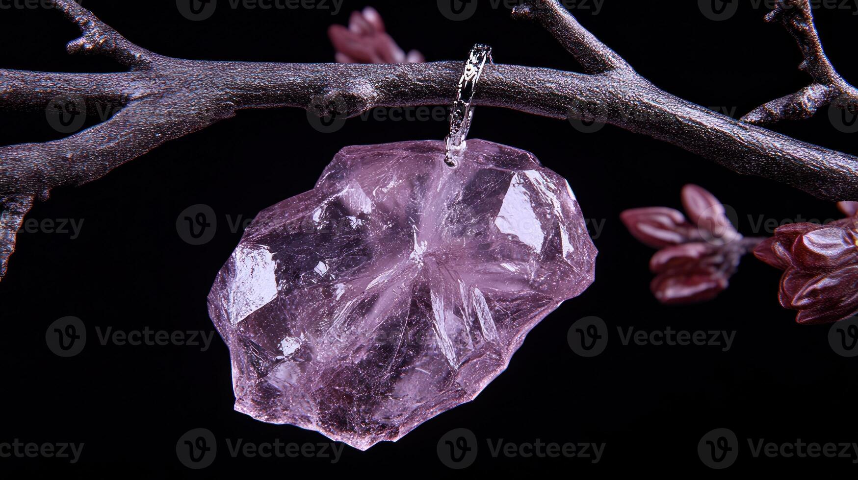 A pink crystal pendant hanging from a branch. photo
