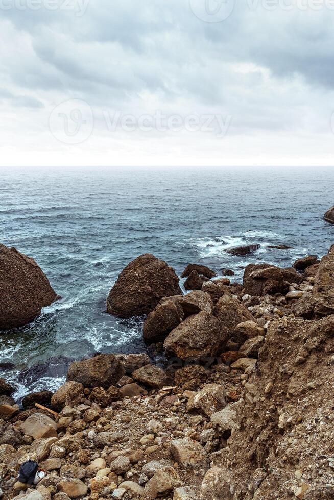 Scenic rocky coastline under overcast sky with waves crashing against stones photo