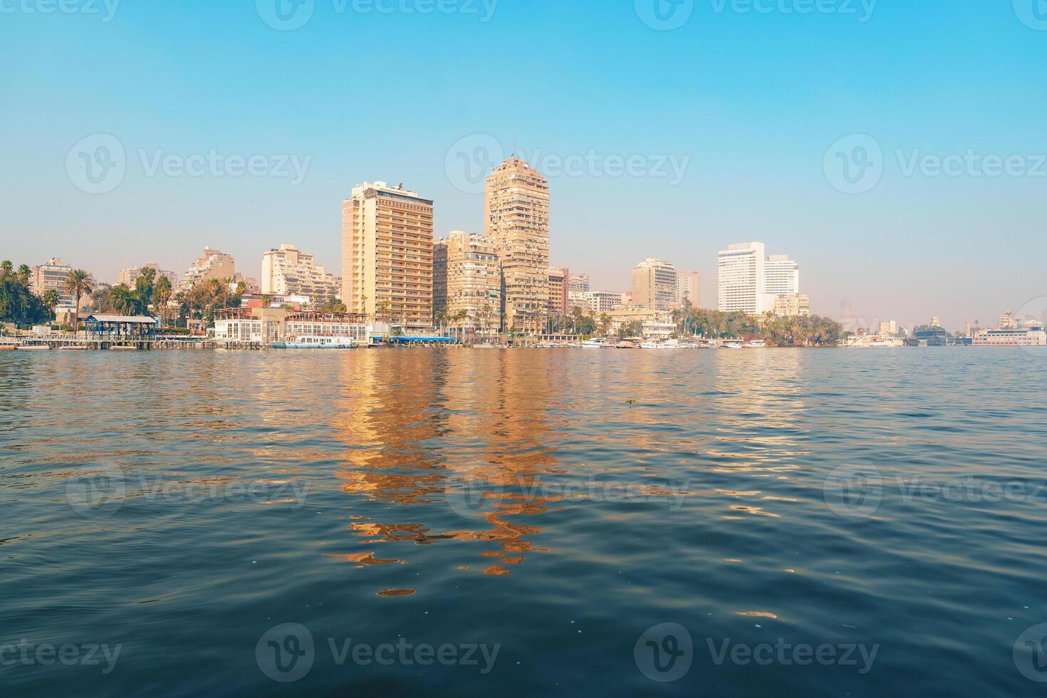 Stunning skyline view of Cairo with blue waters reflecting towering buildings on a clear sunny day photo