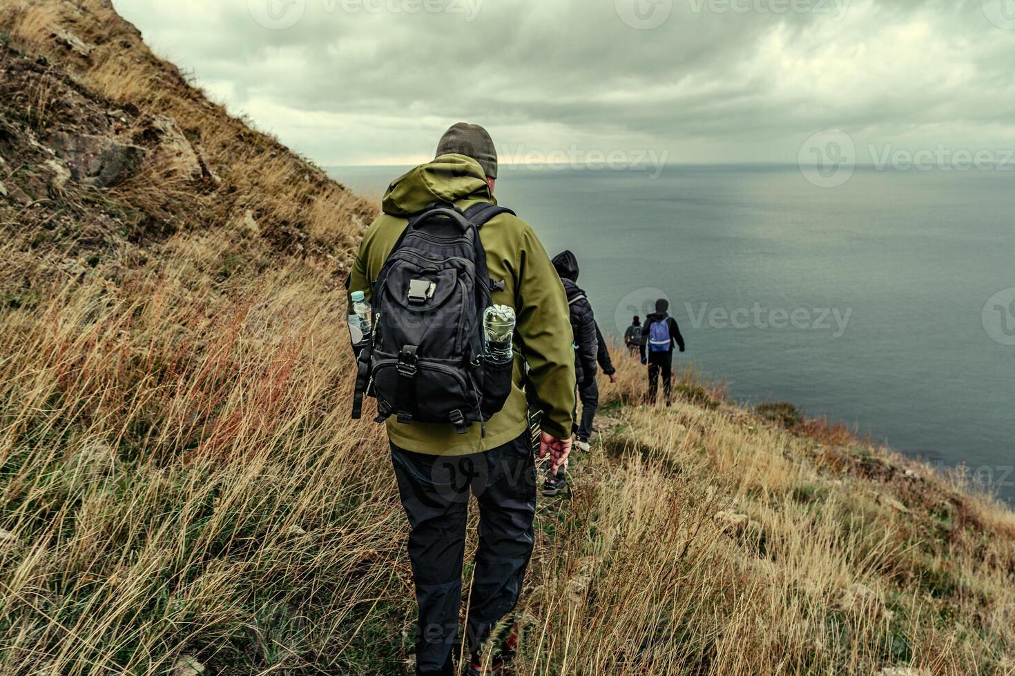 Hiking along a coastal trail with cloudy skies in the background on an overcast day photo