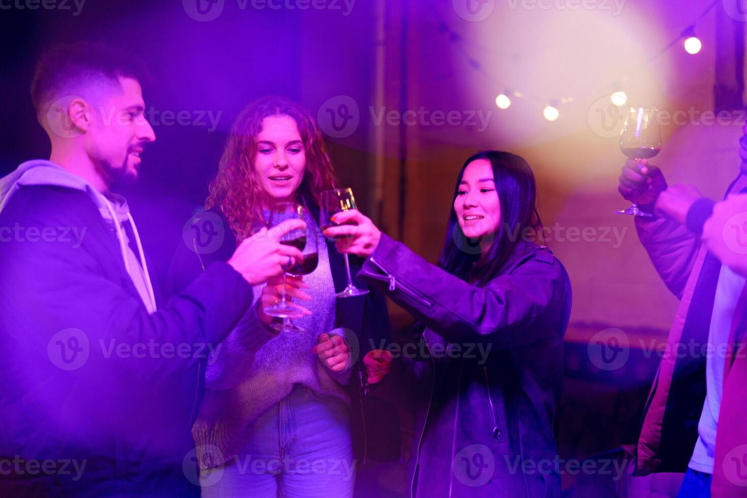 Friends celebrating with drinks in a lively atmosphere during an evening gathering at an outdoor lounge photo