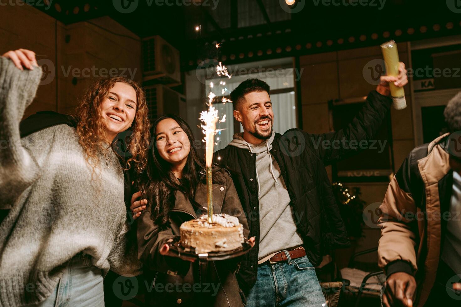 Celebration with friends indoors featuring a birthday cake and sparklers during the evening in a cozy setting photo