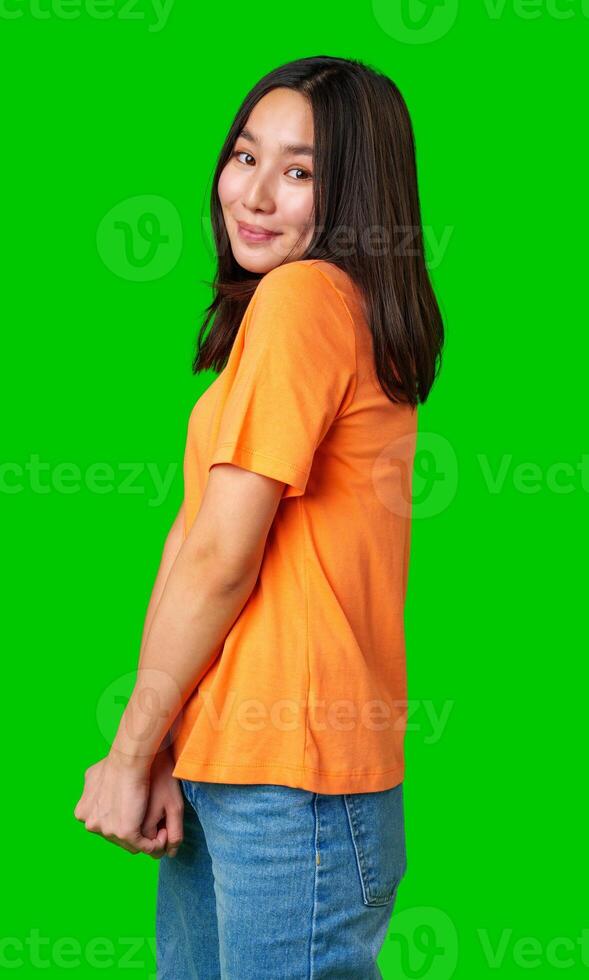 Young woman in orange shirt smiling against bright green background during casual indoor setting photo