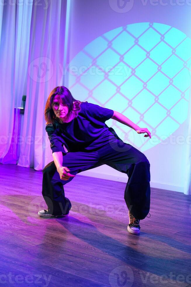 Dancer performing a creative movement in a modern studio with colorful lighting photo