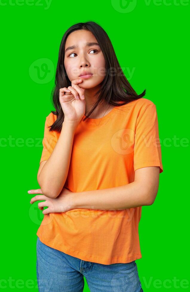 Young woman in orange shirt poses thoughtfully with green background photo