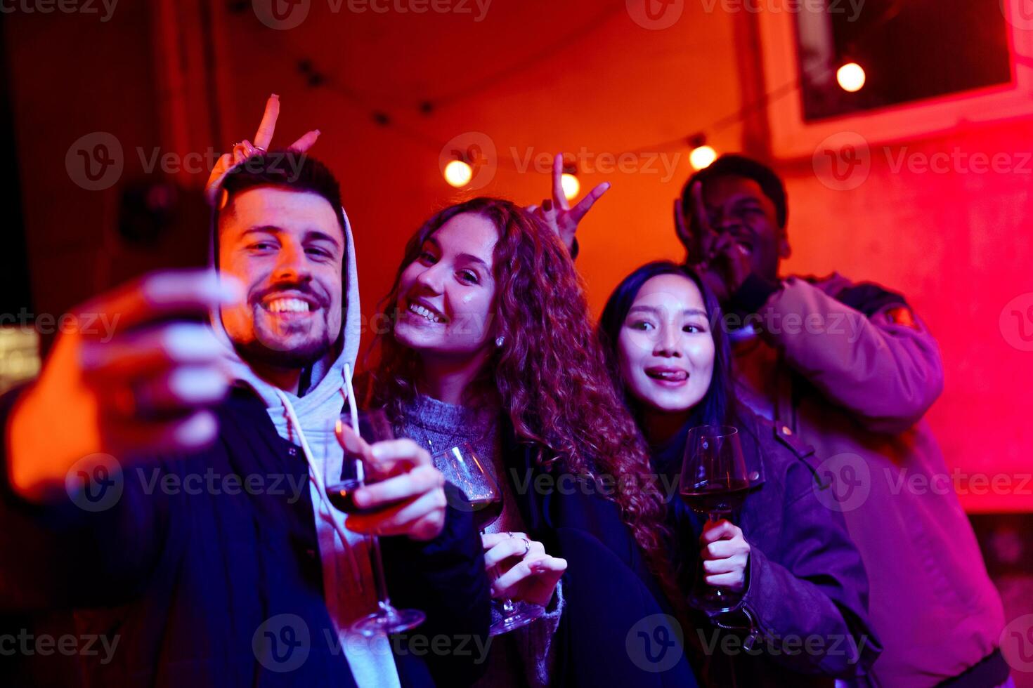 Friends enjoying a night out at a party with drinks and vibrant lights in an urban setting photo