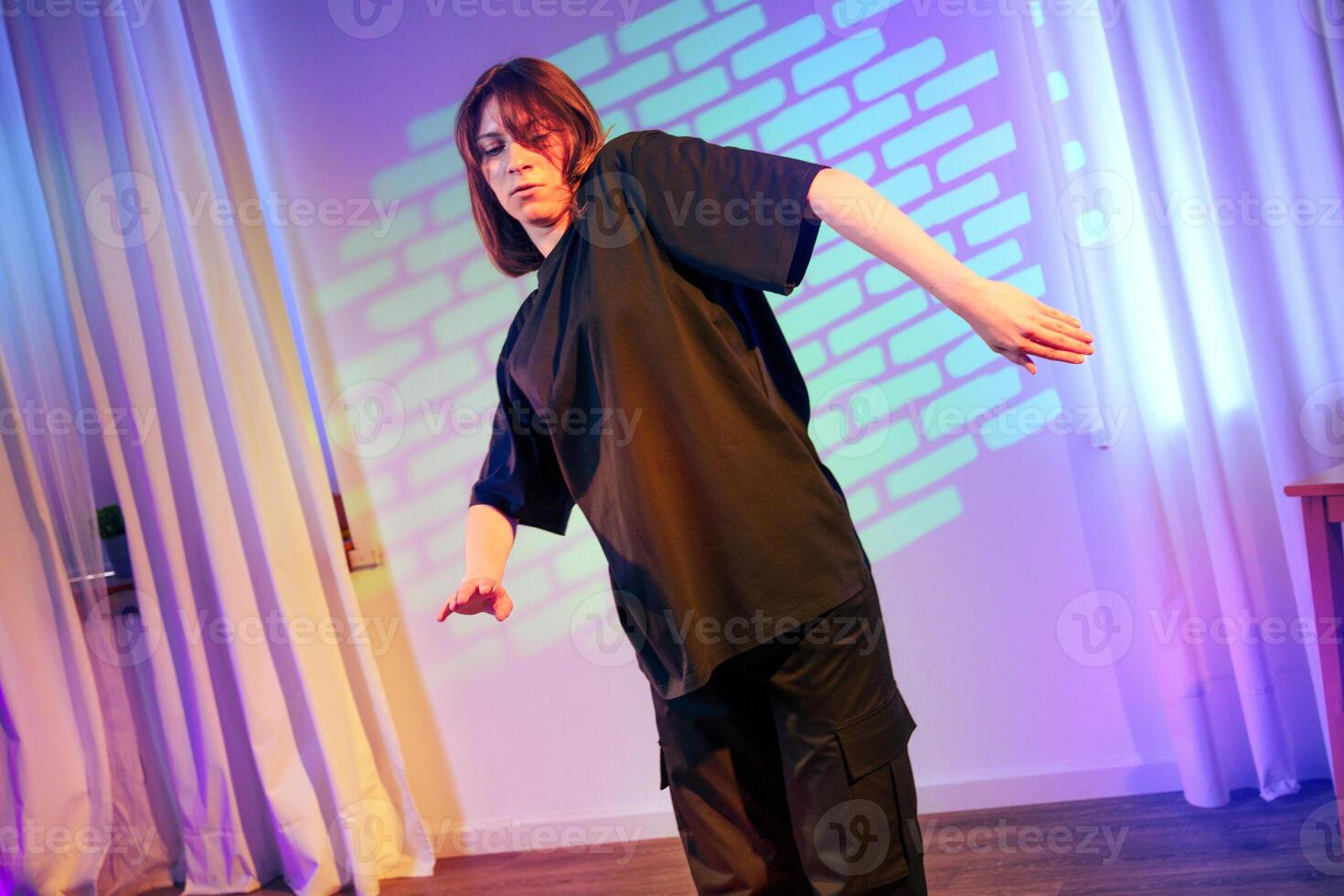 Performer showcasing contemporary dance moves in a dimly lit studio with colorful light projections photo