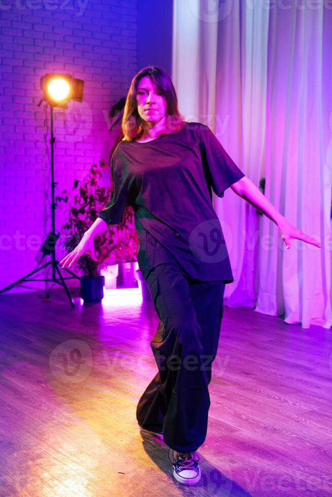 Professional dancer performs in stylish outfit during a vibrant indoor dance session in colorful lighting photo