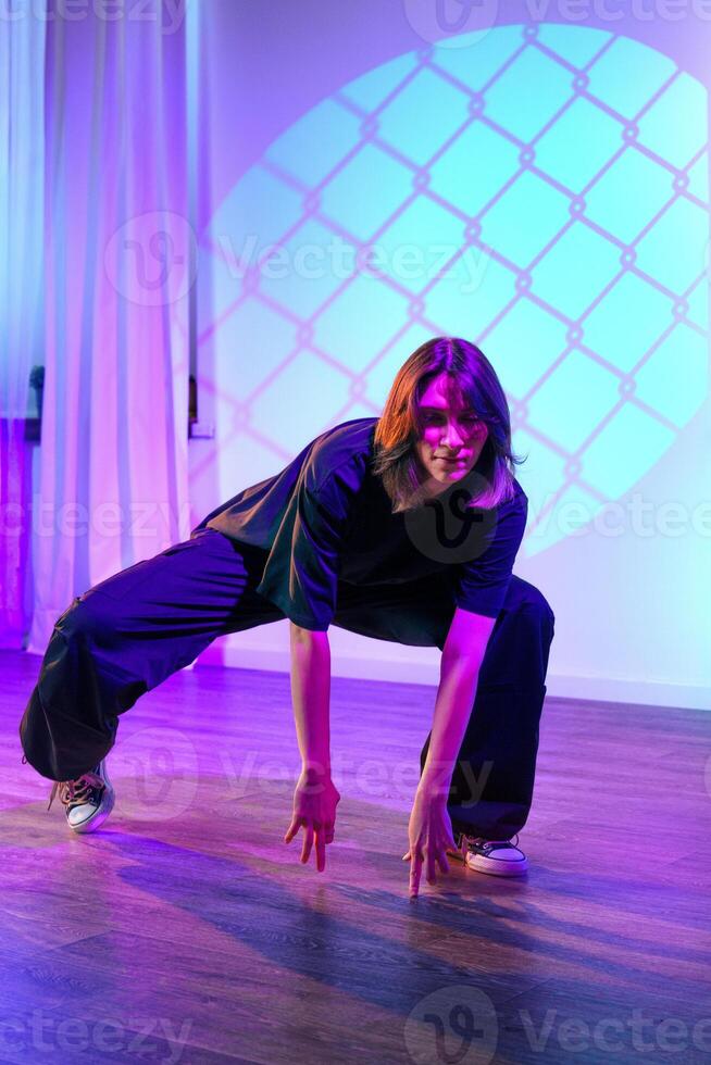 Dynamic dancer performs an expressive routine in a colorful studio setting with vibrant lighting effects photo