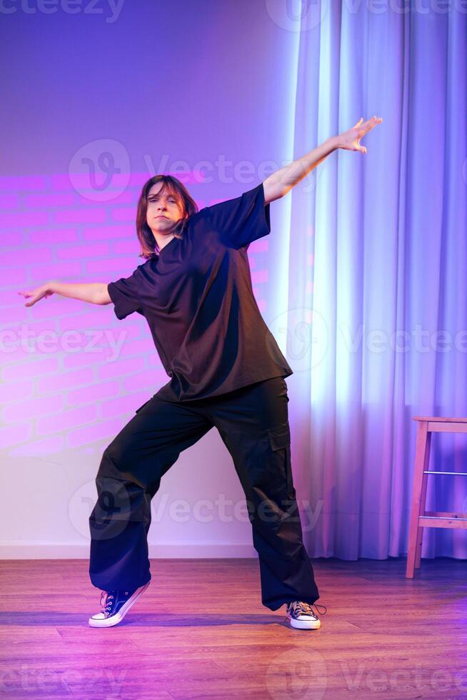 Dance performance featuring a person in casual black attire against a colorful backdrop in a studio setting photo