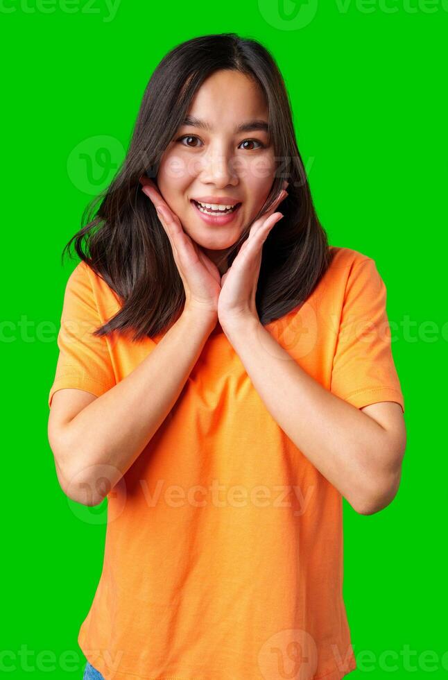 Excited young woman expressing joy with hands on her face against a bright green background photo