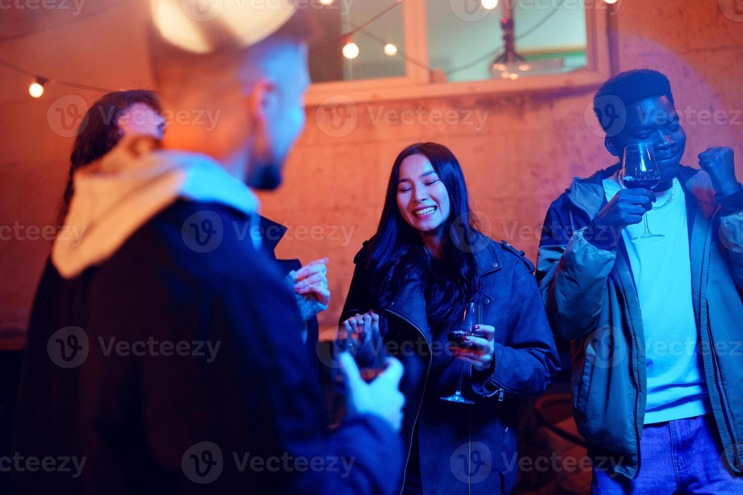 Friends enjoy an evening gathering with drinks while celebrating under string lights in an outdoor setting photo
