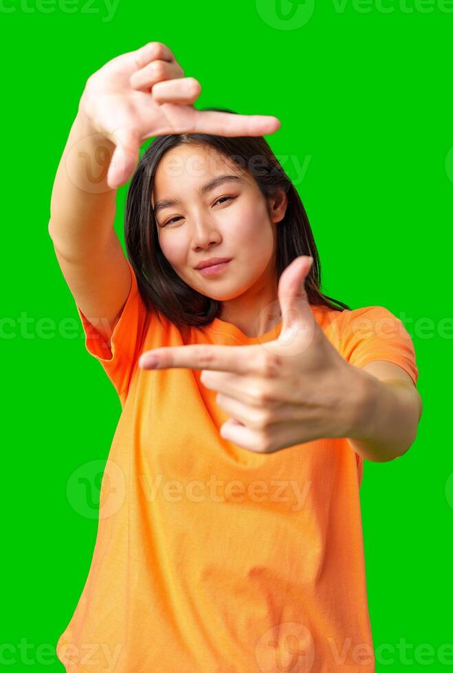 Dynamic young woman playfully framing a shot with her hands against a bright green background in an energetic setting photo