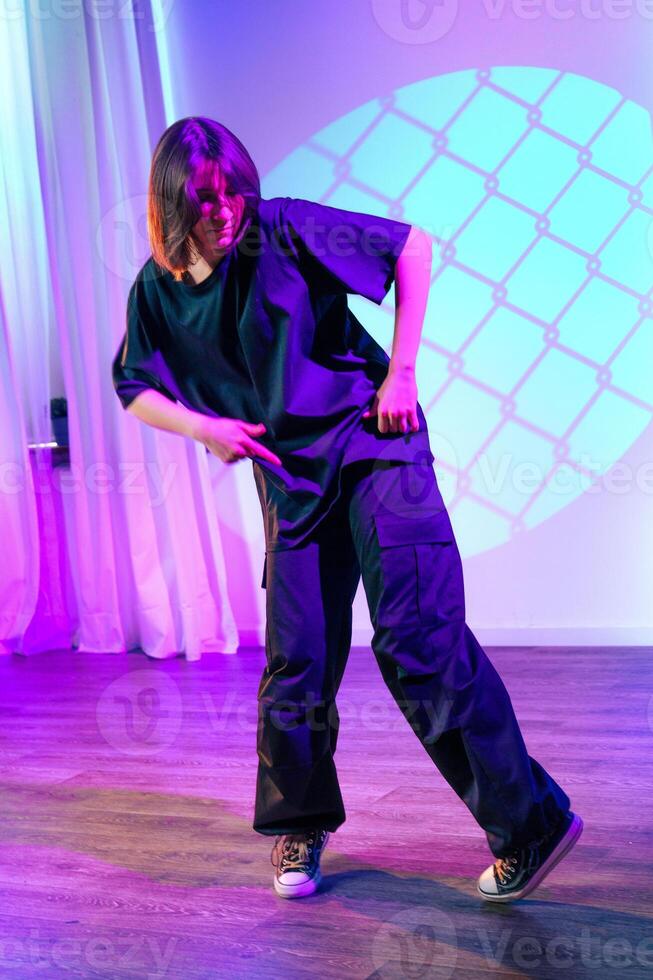 Dancer performing an expressive routine in a contemporary studio space with colorful lighting and shadows photo