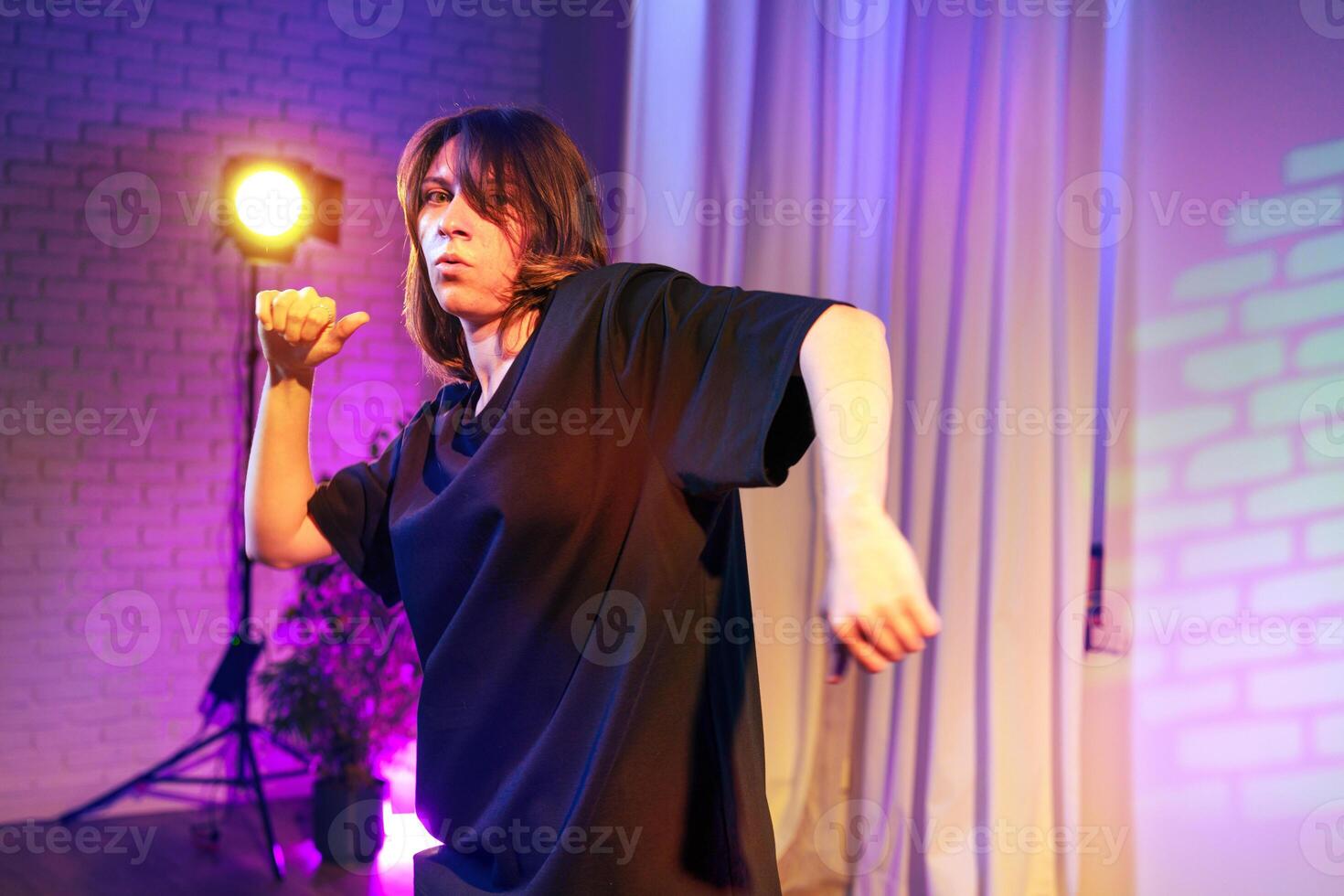 Dance performance featuring a dancer in a relaxed outfit under colored stage lights during an evening event photo