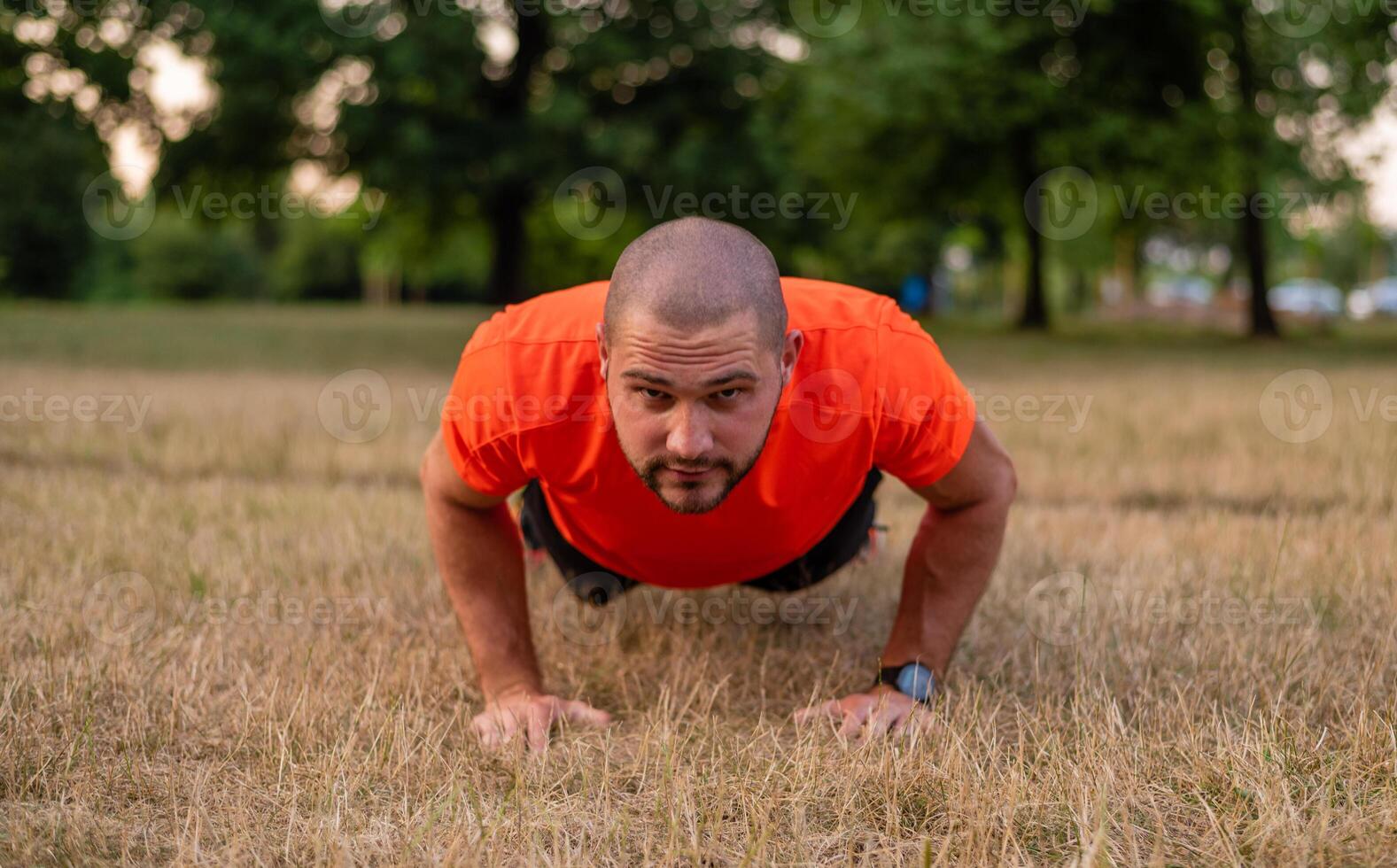 A sporty man is doing push up exercises before workout outdoor in the summer park active healthy lifestyle. photo