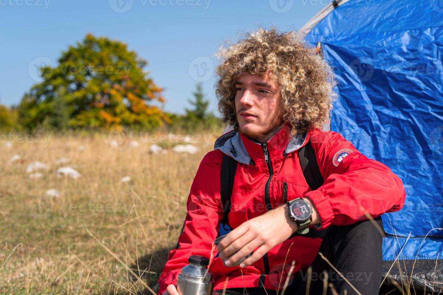 A happy young traveler enjoying while drinking a cup of coffee during the camping on the mountain forest. photo