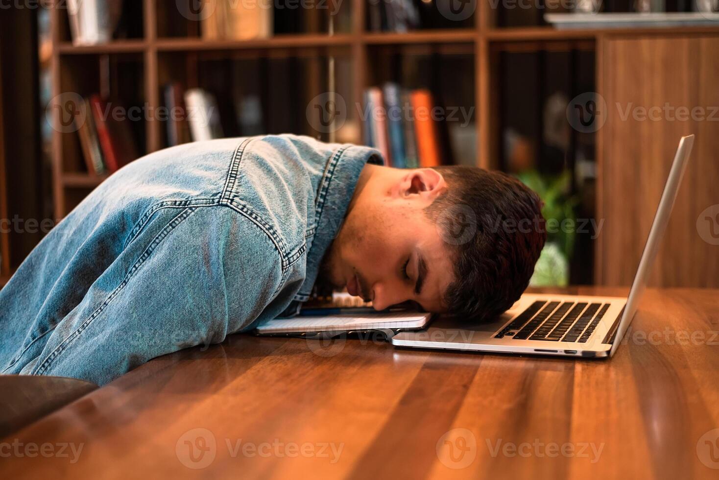 A tired student sleeping on the table inside university library. photo