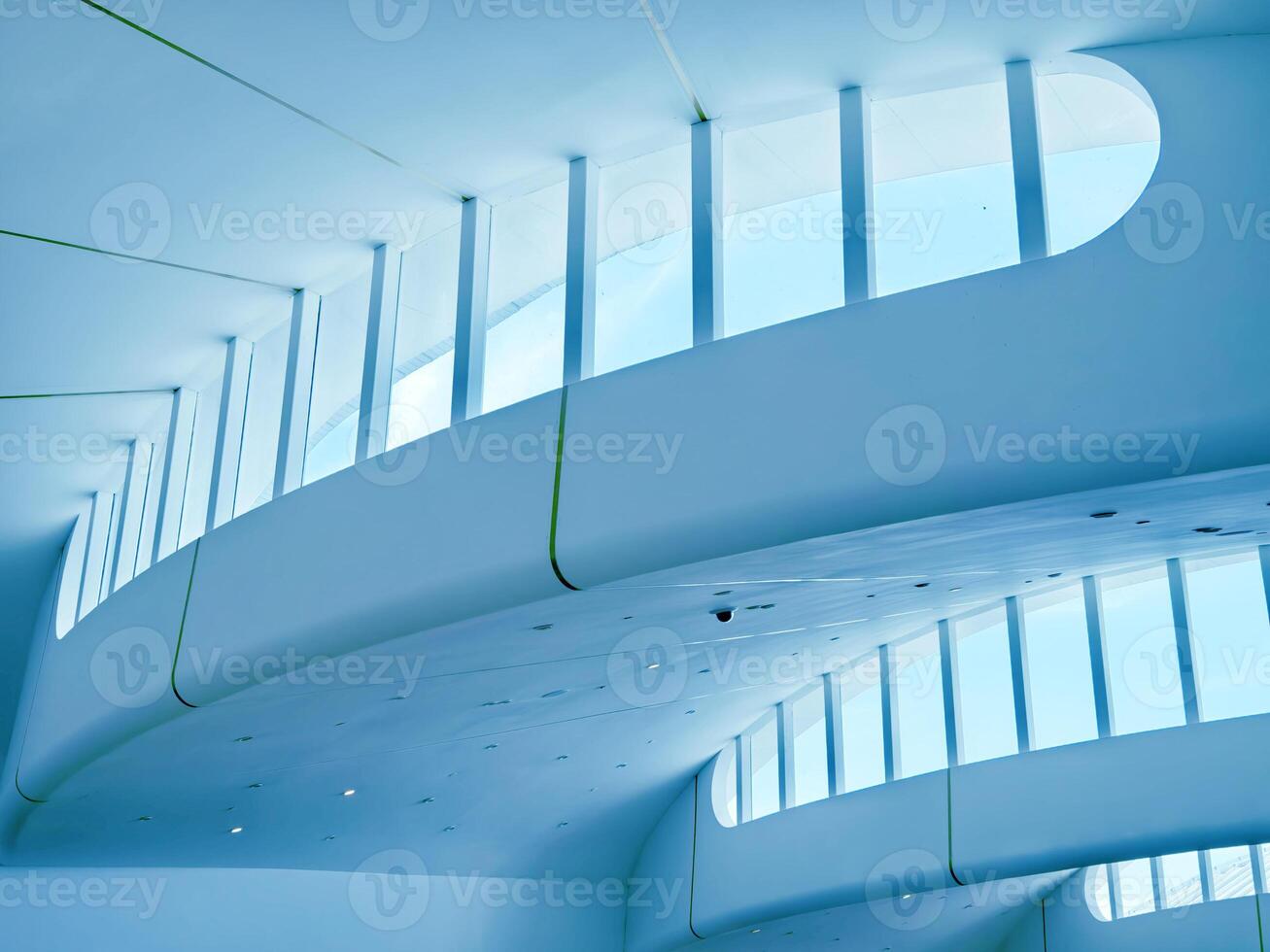 The ceiling of a vast building that features numerous windows photo