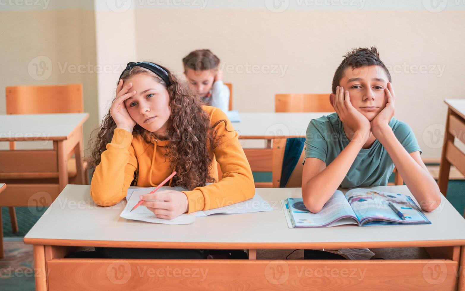 Tired and bored child students sitting in a school desk during the class. photo