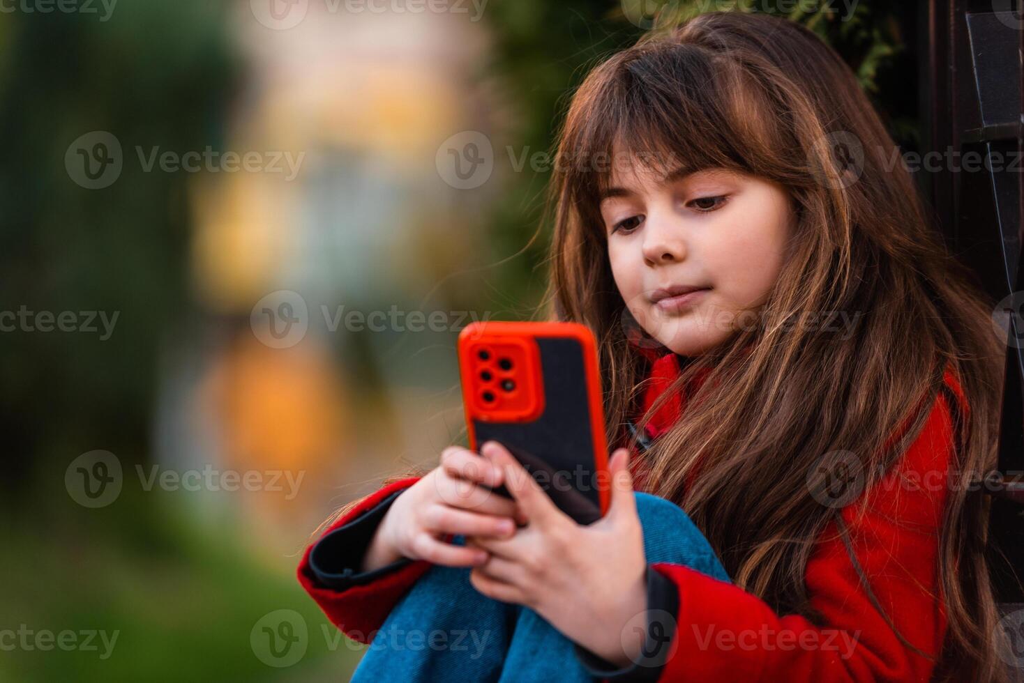 A happy little girl using a phone outside. photo