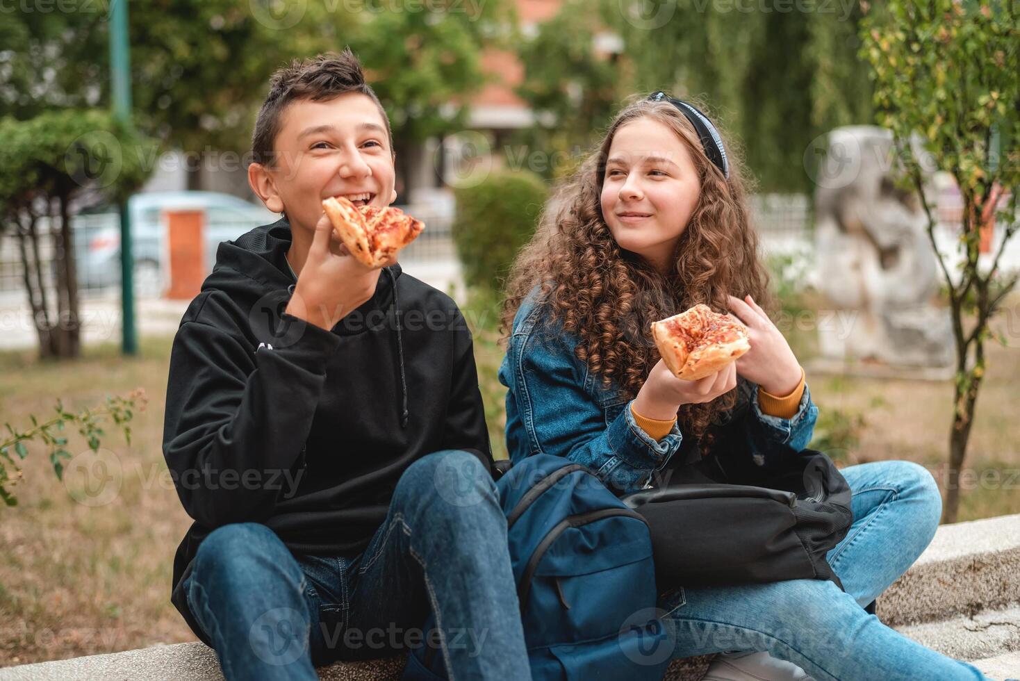 Happy friends students having a fun while eating a pizza sandwich on a school lunch break. photo