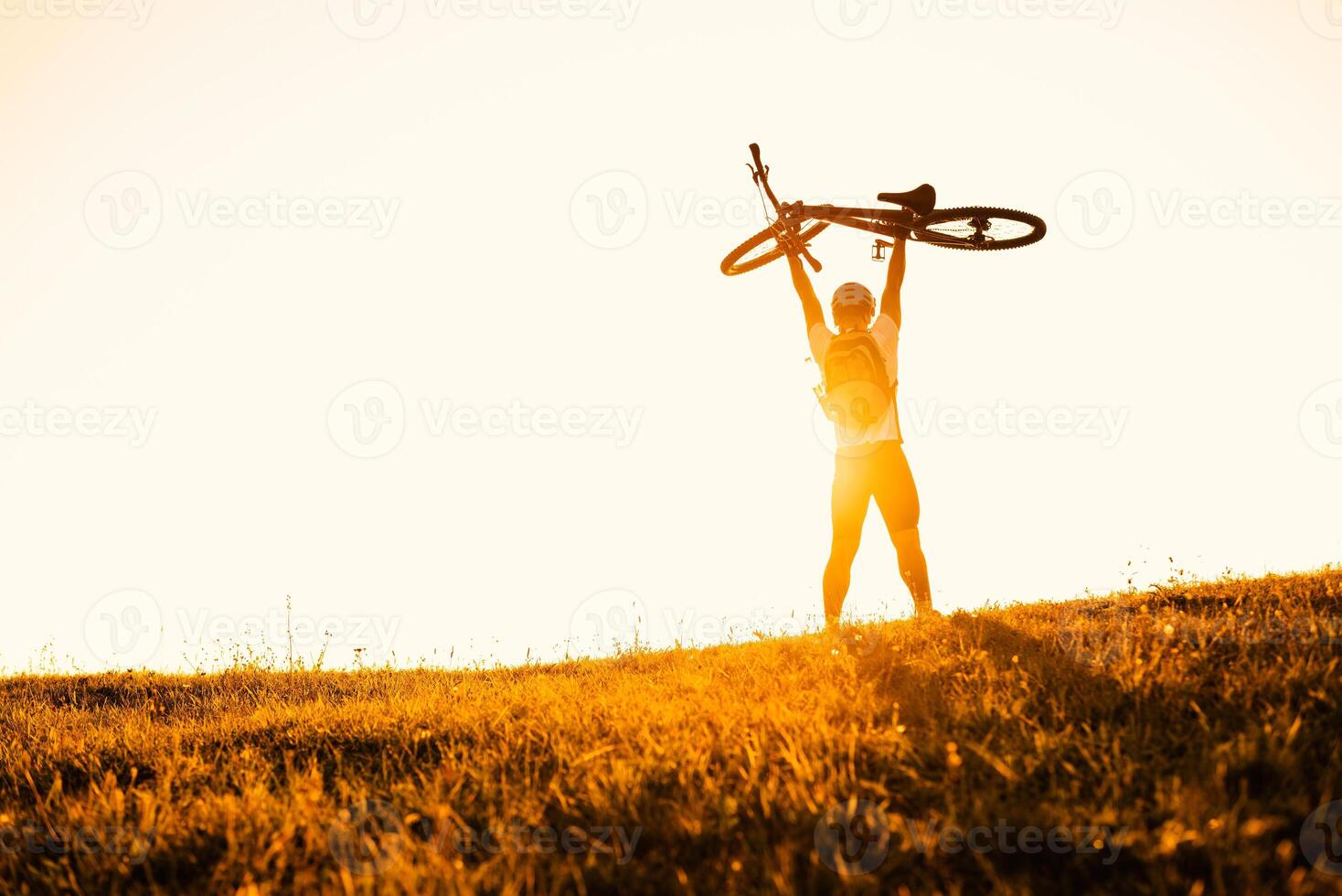 Happy male cyclist celebrating victory holding his bicycle over himself active lifestyle. photo