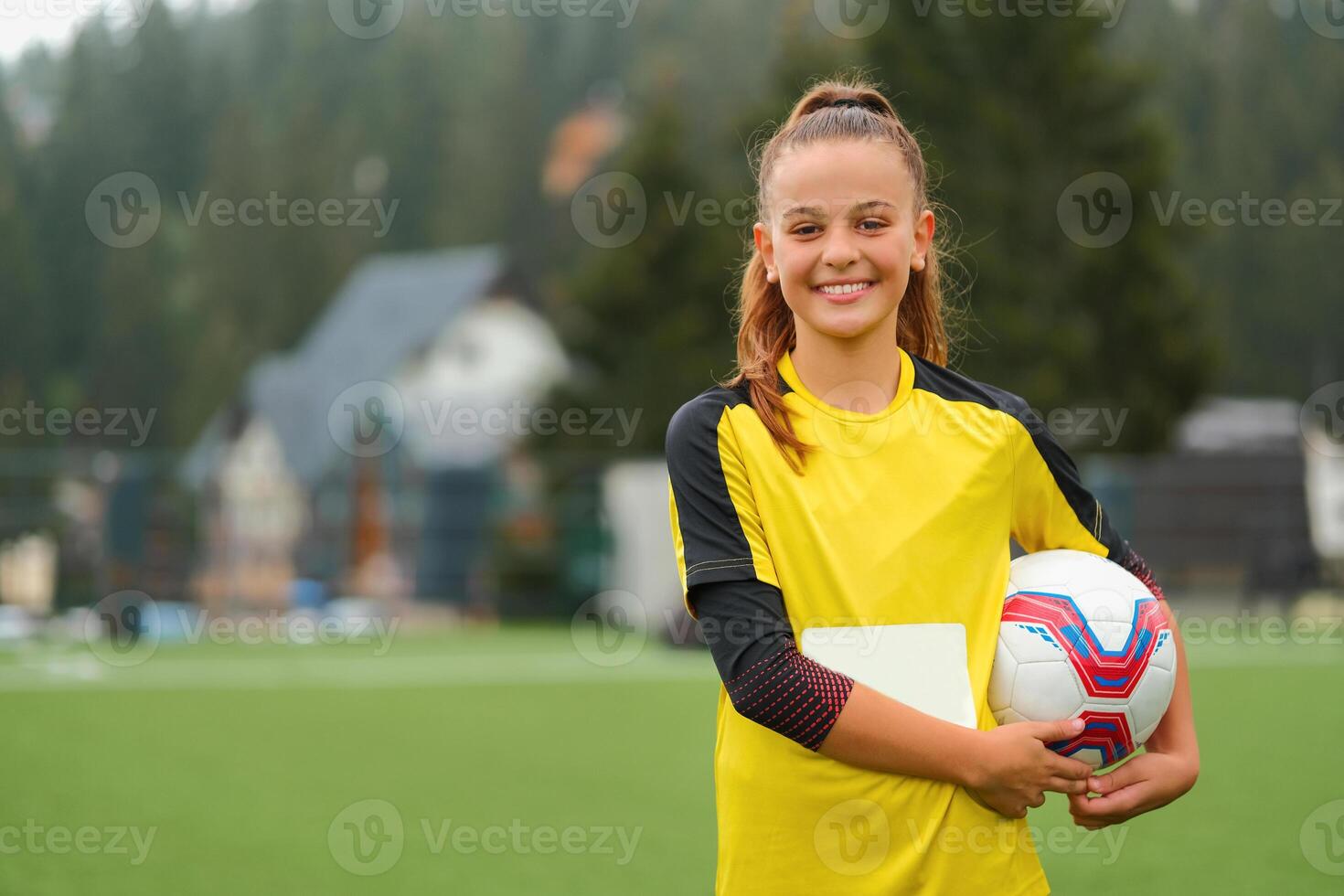 Portrait of a happy female soccer player on the football field with a soccer ball in her hand. photo