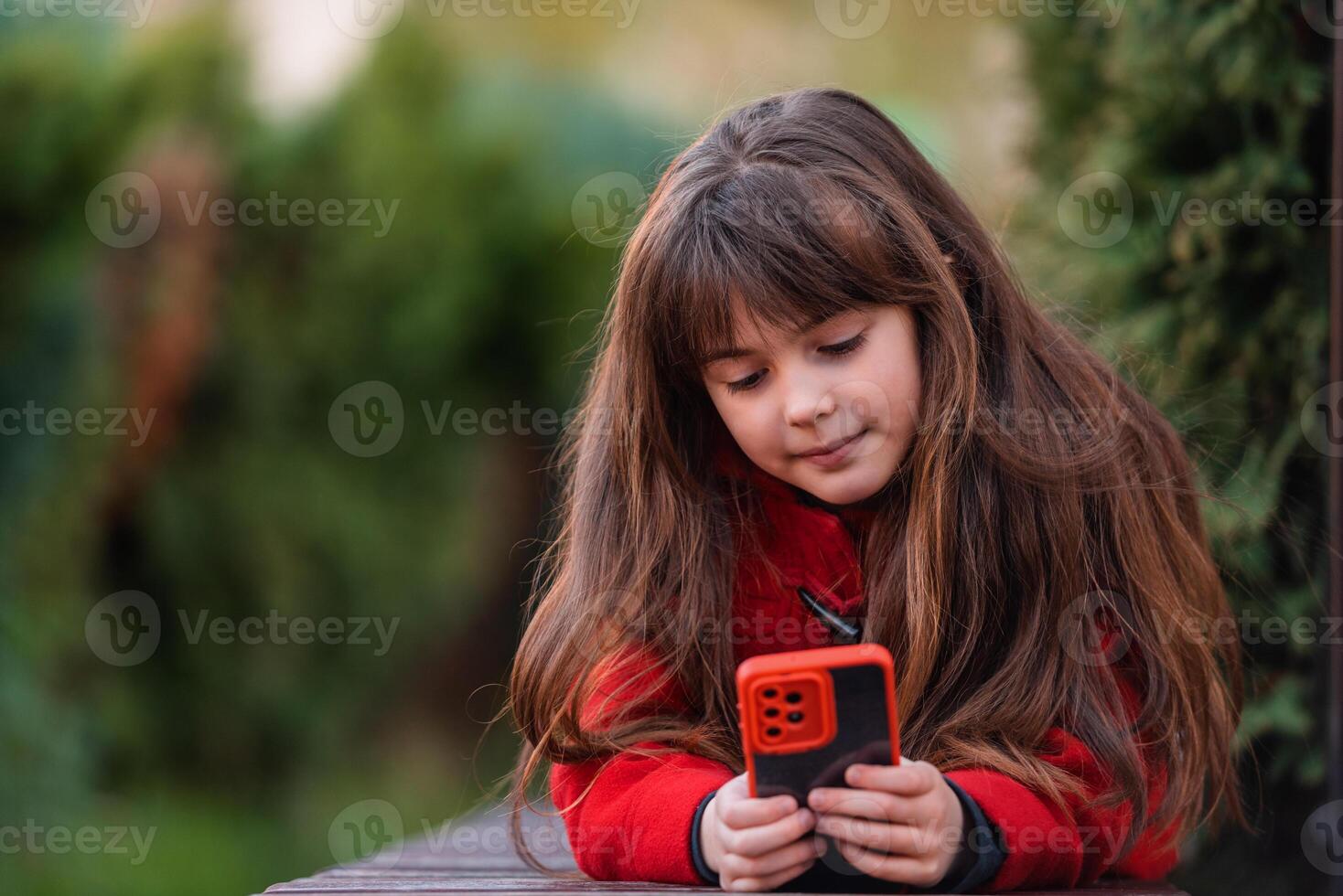 A happy child girl using a phone outside. photo