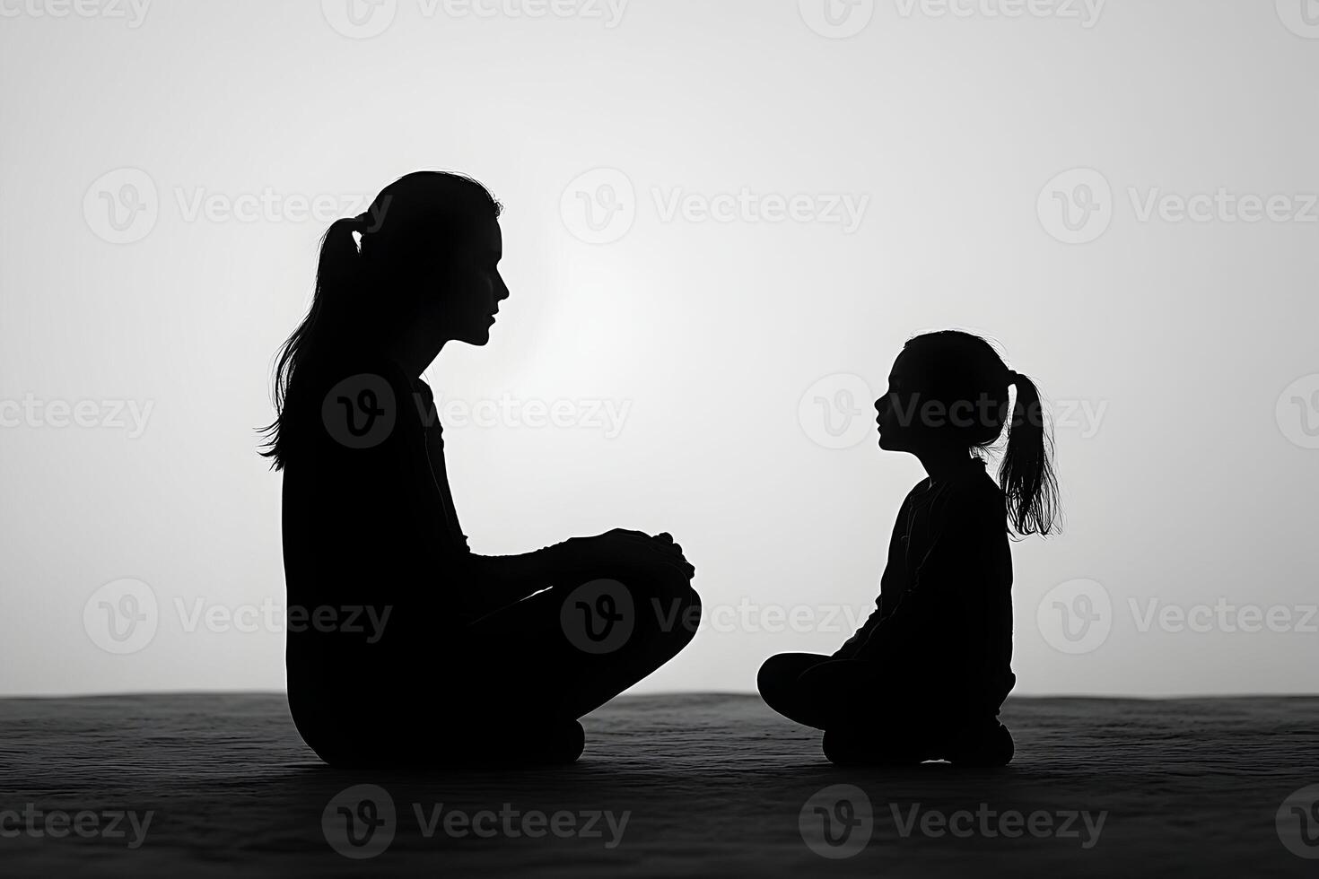 Silhouette of a mother and daughter sitting on the ground photo
