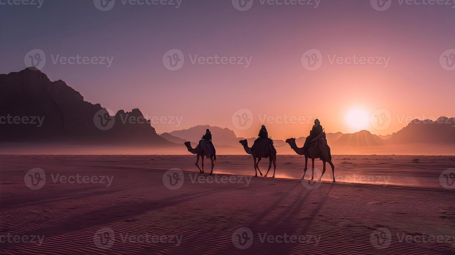 Camels traversing the desert at sunset with mountains in the background and a pink and orange sky photo