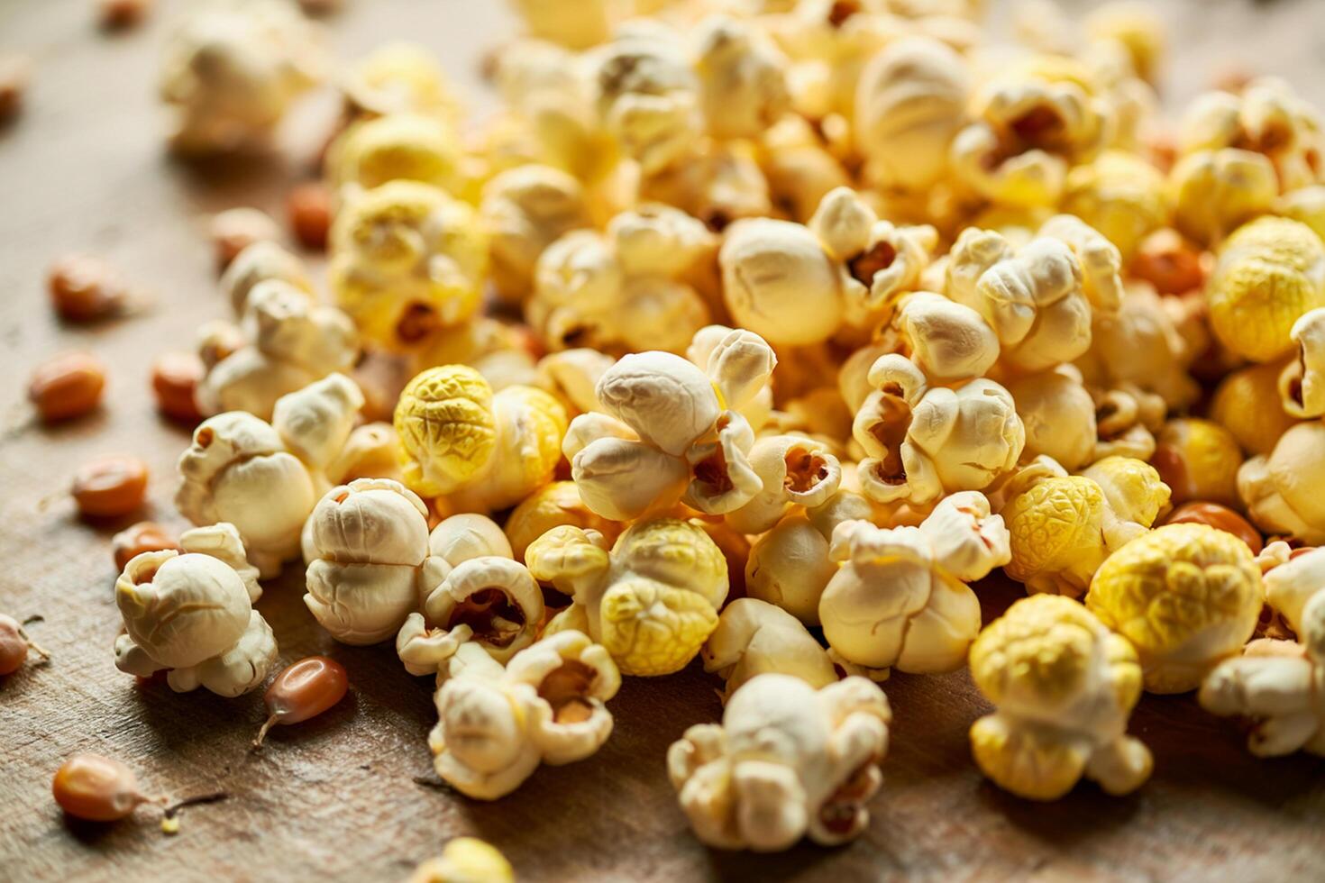 Close Up Of Yellow Popcorn And Kernels Scattered On A Wooden Surface photo